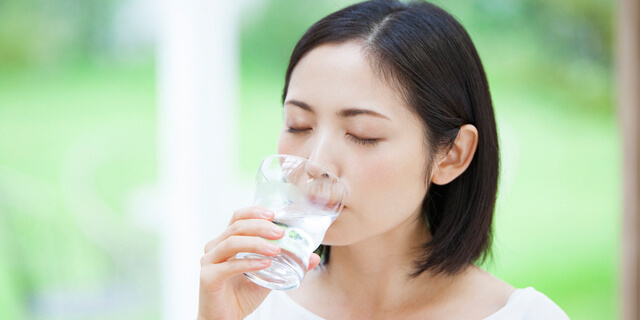 水が入ったグラスを持つ女性