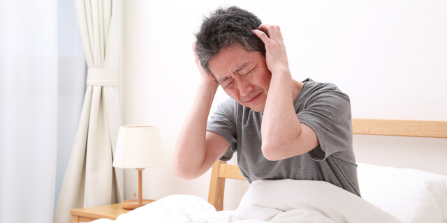 ベットで頭を抱える男性
