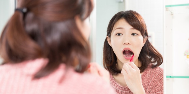 鏡を見ながら歯磨きする女