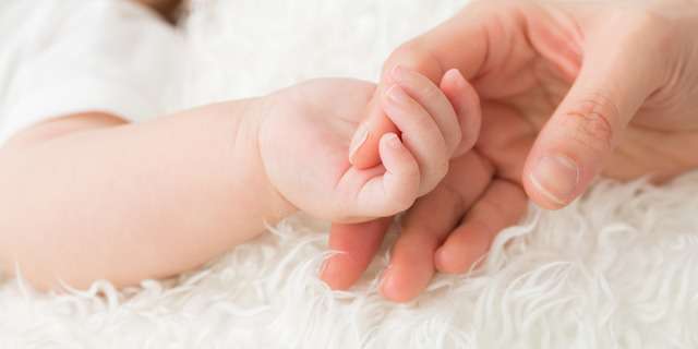新生児の手を握る