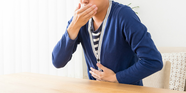 お腹と口を押さえる男性